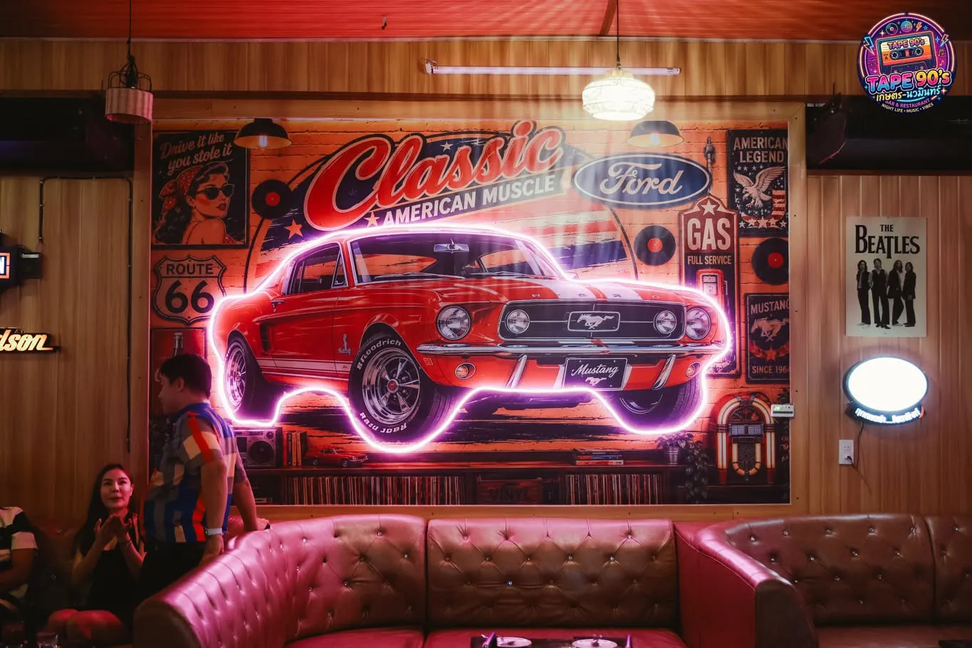 Góc quán với neon xe Mustang đỏ và ghế da