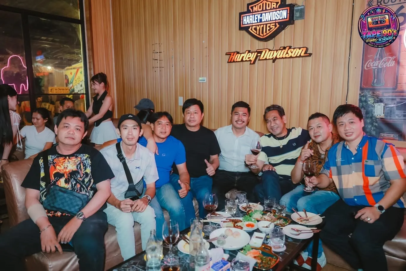กลุ่มลูกค้านั่งโซฟาหน้าป้าย Harley-Davidson