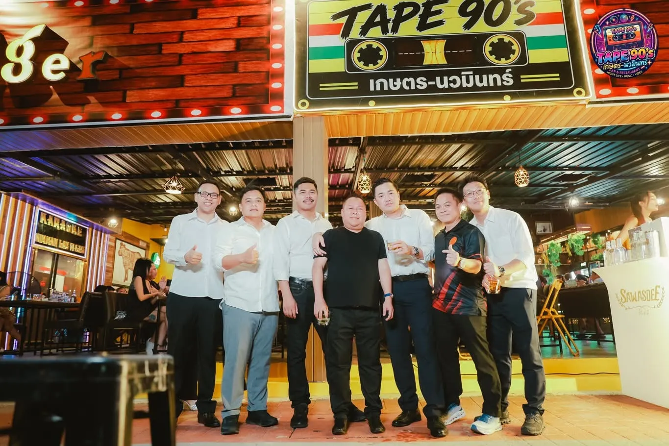 กลุ่มลูกค้ายืนถ่ายภาพหน้าป้ายร้าน