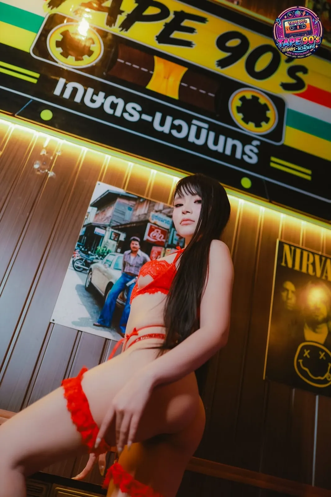 นางแบบสวมชุดชั้นในสีแดงหน้าป้ายไฟของร้าน
